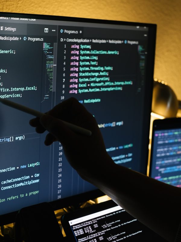 Man working at night coding and pointing on a screen with a pen